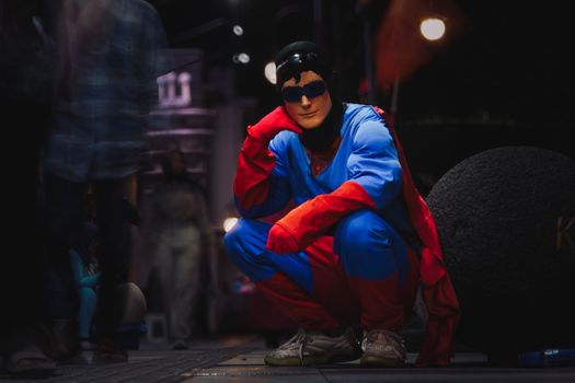 A person dressed as a superhero crouches on a night street in Jawa Barat, Indonesia.