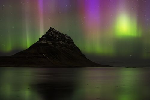 Free Vibrant northern lights dance over Iceland's iconic Kirkjufell mountain at night. Stock Photo