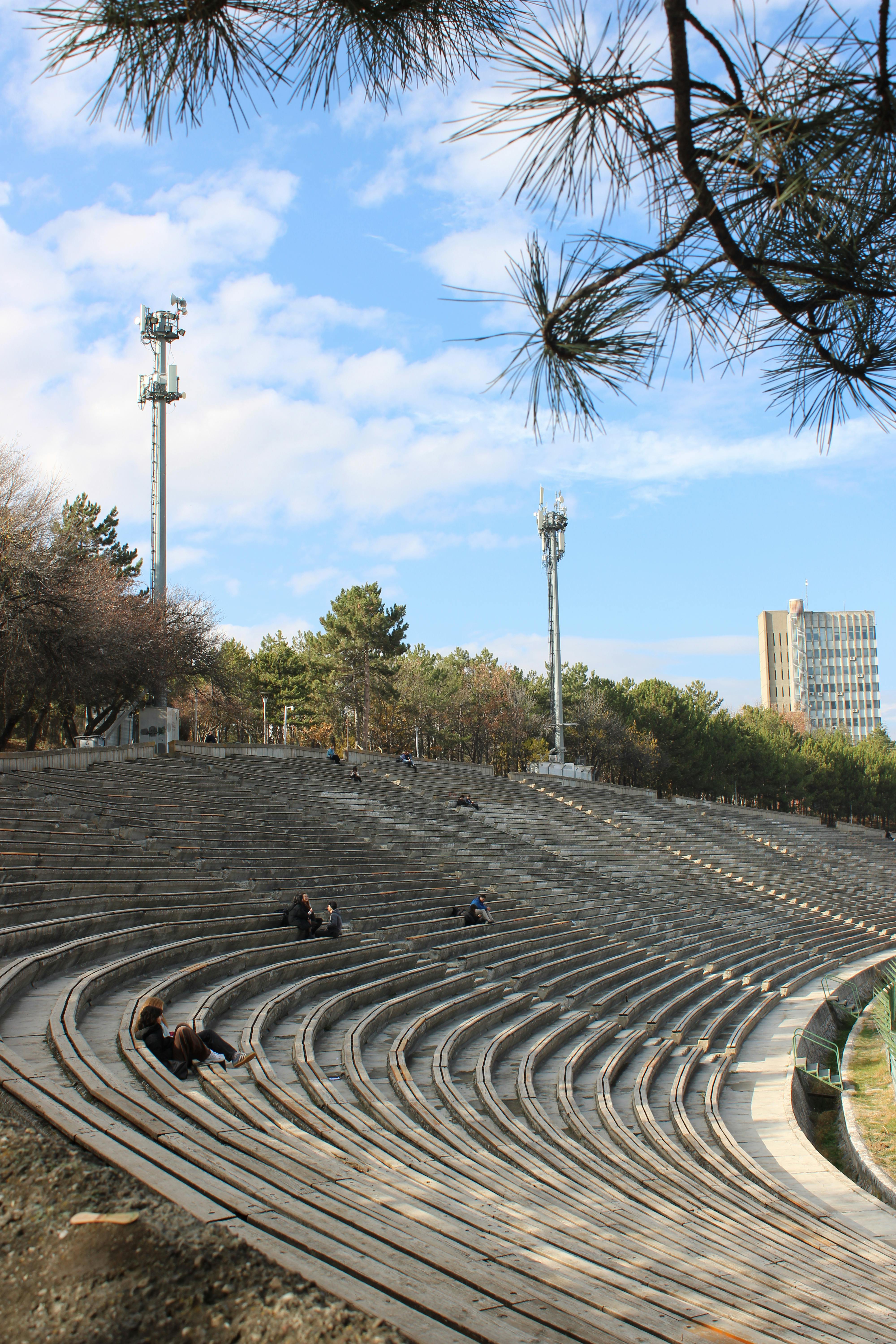 Free Empty amphitheater with cloudy sky and trees, serene setting. Stock Photo