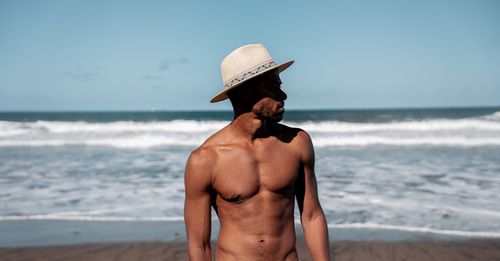 Free A man wearing a hat enjoys a sunny day on a beach in the Canary Islands with waves in the background. Stock Photo
