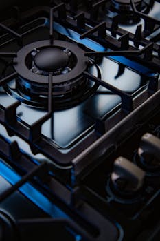 Detailed view of a modern gas stove burner highlighting its sleek and glossy design with blue lighting.