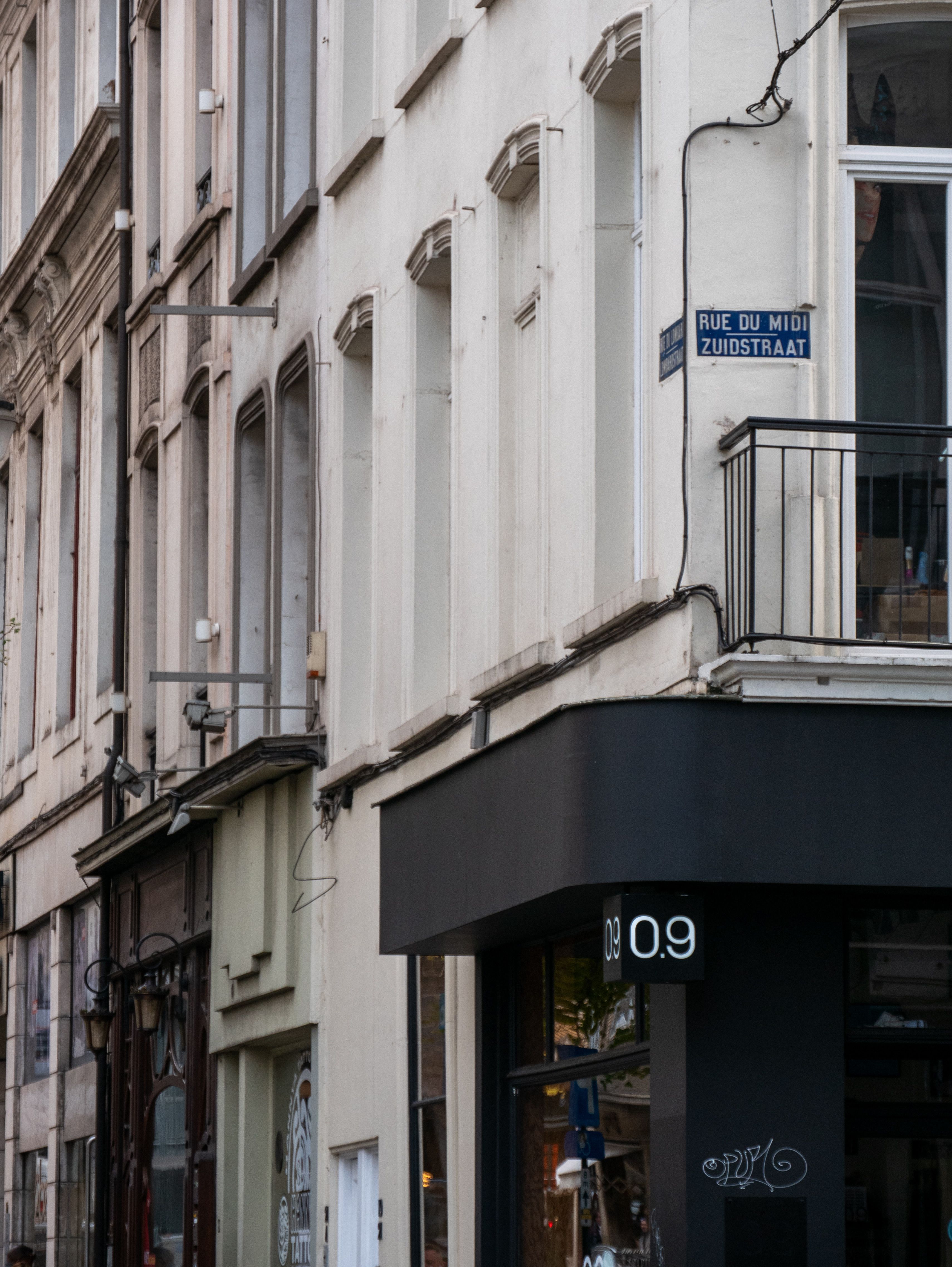 A European city street featuring classic architecture and a bilingual street sign.