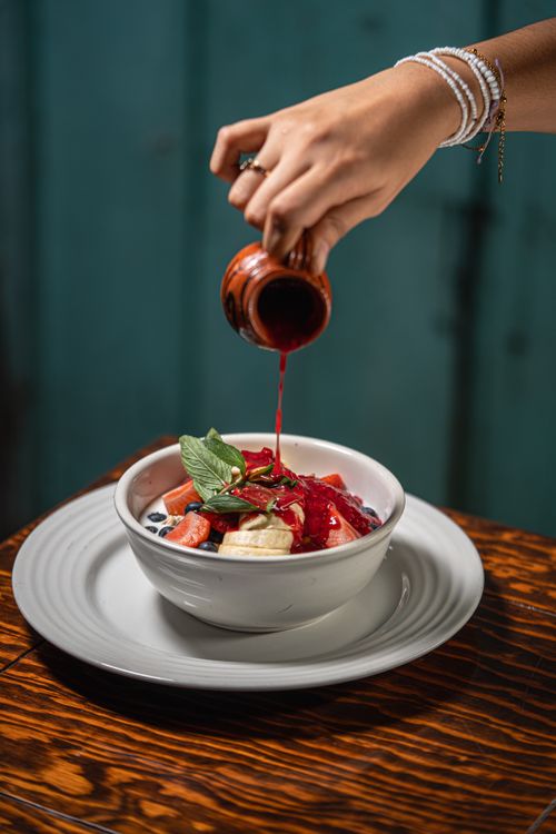 Free A vibrant berry smoothie bowl topped with fresh fruit and sauce pouring from a jug. Stock Photo