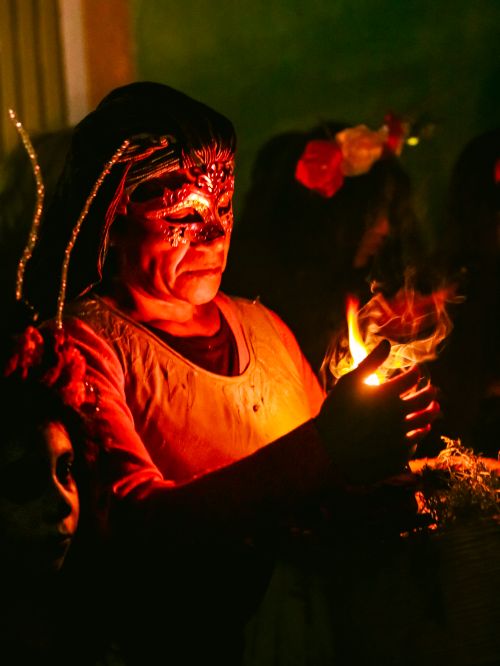 Free Person in elaborate masquerade mask holding a glowing candle, creating an eerie and festive atmosphere. Stock Photo