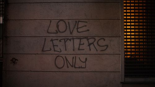 Free Street wall graffiti reading 'LOVE LETTERS ONLY' with urban atmosphere. Stock Photo