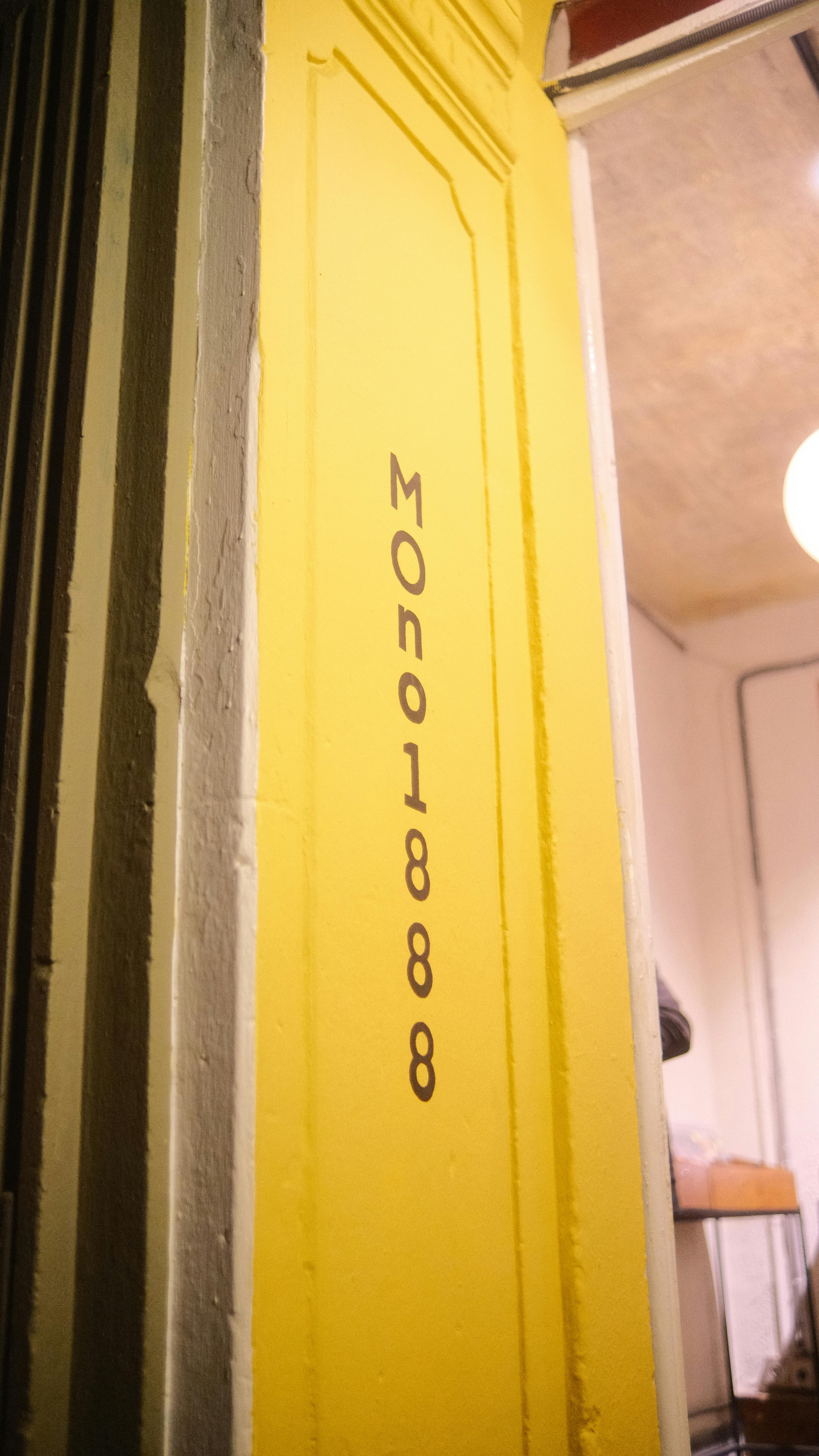grátis Detalhe de uma moldura de porta amarela com a inscrição 'Mono1888' no interior. Foto profissional