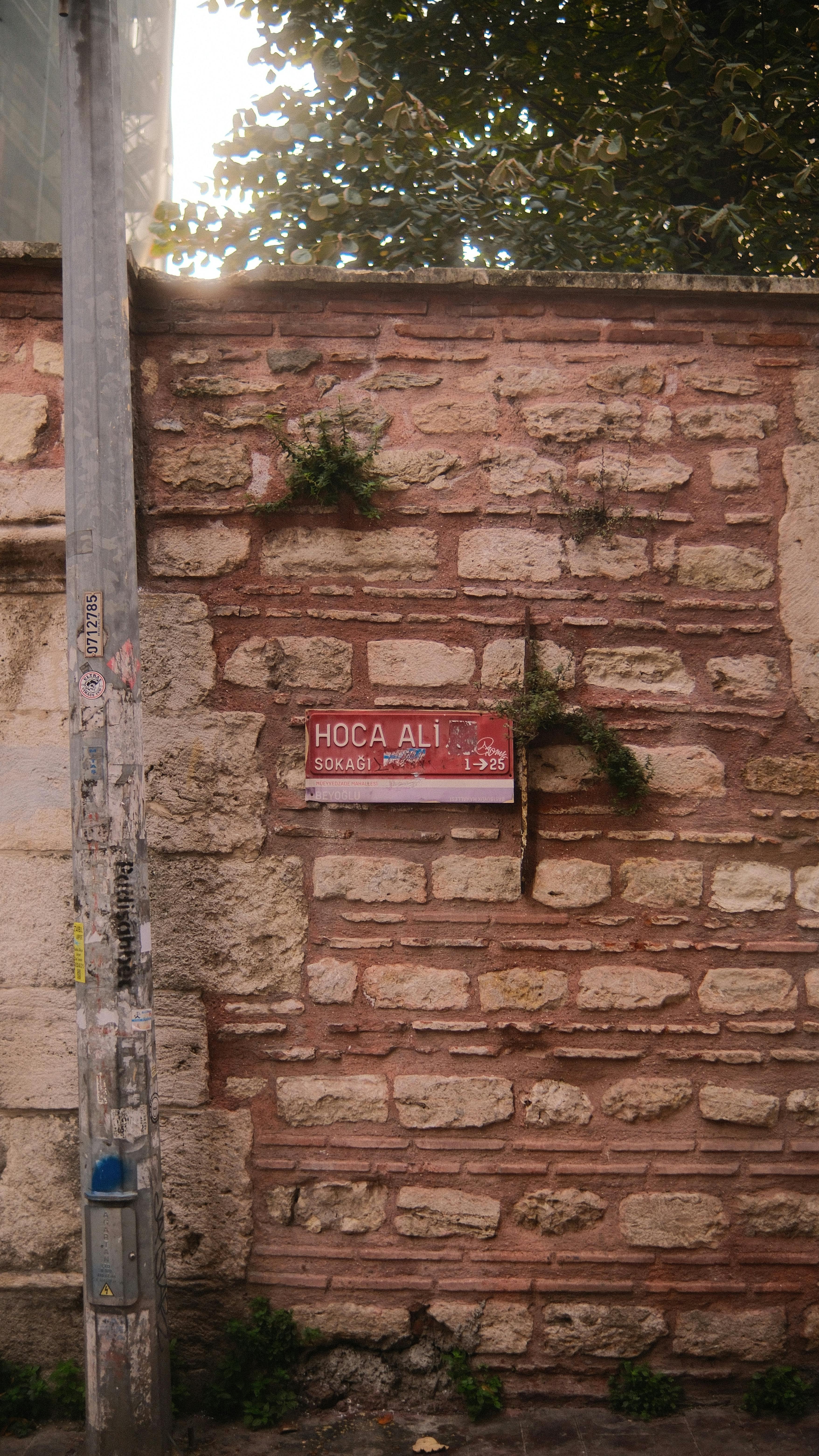 Kostenlos Urbanes Straßenbild mit historischer Backsteinmauer und dem Schild „Hoca Ali Sokak“ bei Tageslicht. Stock-Foto