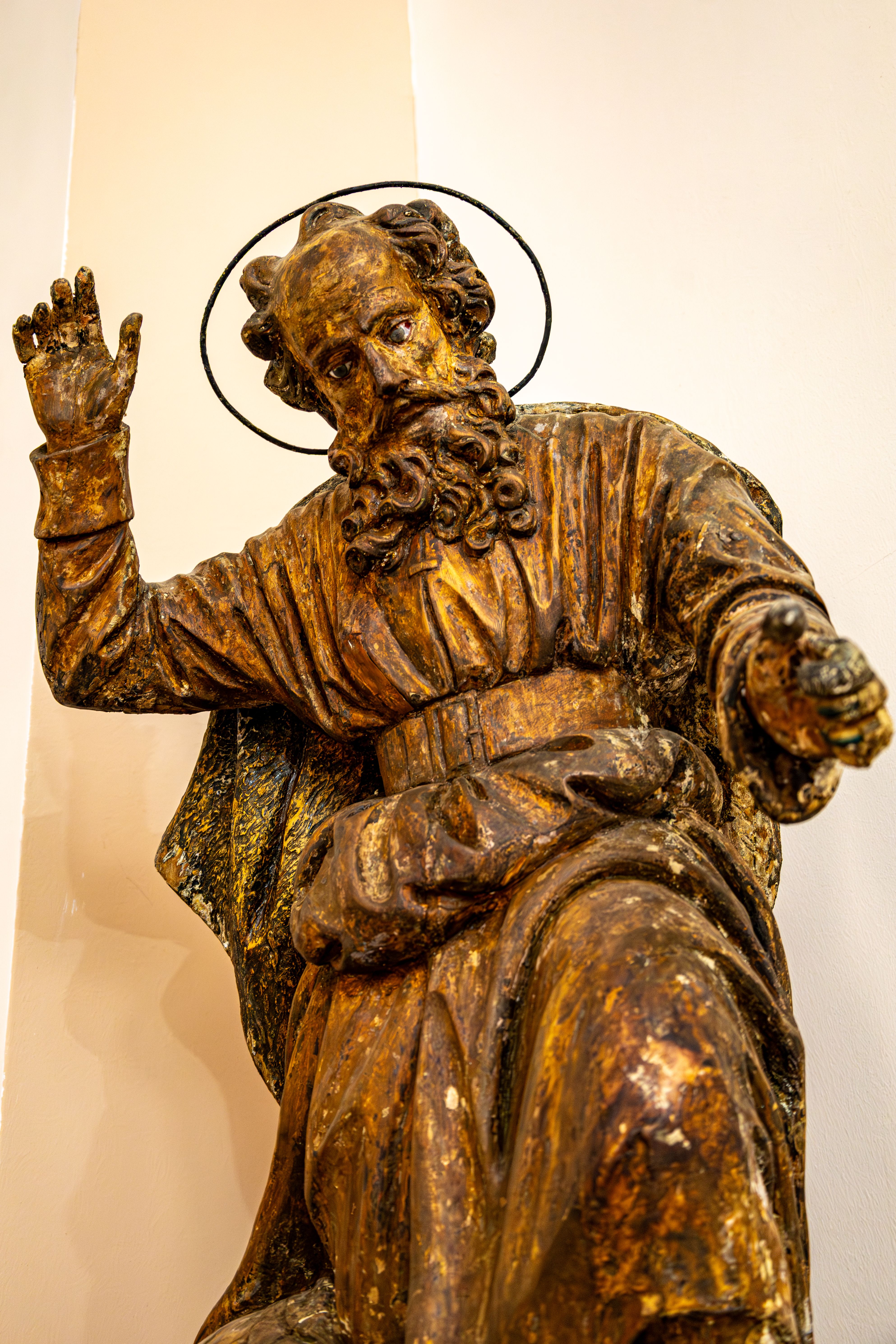 Close-up of vintage wooden religious statue with halo inside a church.