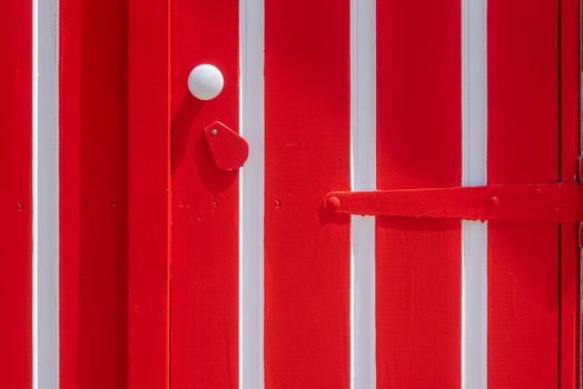 Close-up of a red and white wooden door featuring strong geometric patterns and bold colors.