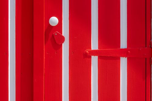 Free Close-up of a red and white wooden door featuring strong geometric patterns and bold colors. Stock Photo