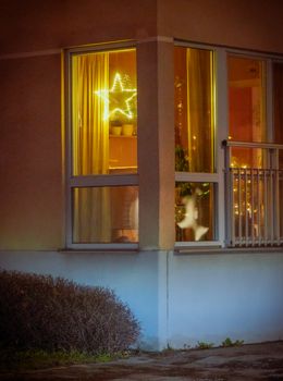 Warm festive glow through an apartment window with star-shaped holiday lights.