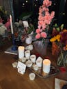 A serene candlelit tribute with pink carnation arrangement and white candles.
