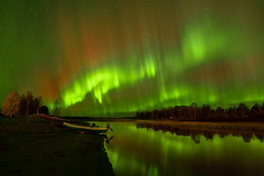 Aurora Borealis lights up the night sky with boats reflecting in a tranquil lake.