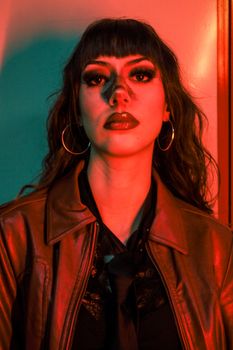 A striking portrait of a woman with bold makeup, highlighted by dramatic red and green lighting.
