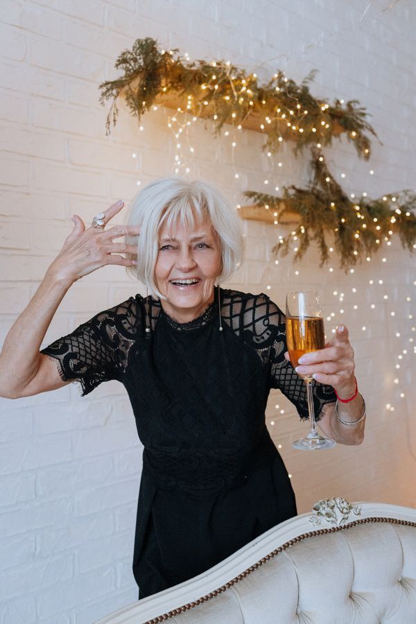 Joyful mature woman in black dress celebrating