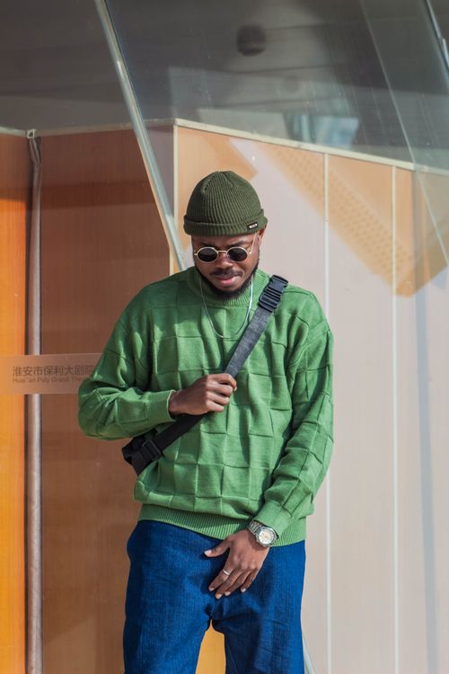 Free A fashionable adult man poses confidently in a green sweater and beanie, showcasing urban style. Stock Photo