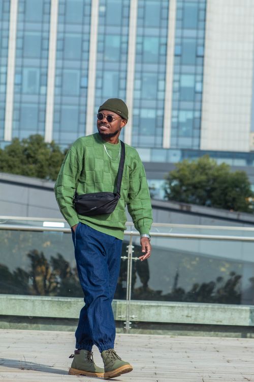 Free Stylish man walking outdoors in casual urban fashion against city backdrop. Stock Photo