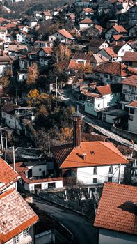 A picturesque village with red-tiled roofs viewed from above, showcasing autumn colors.