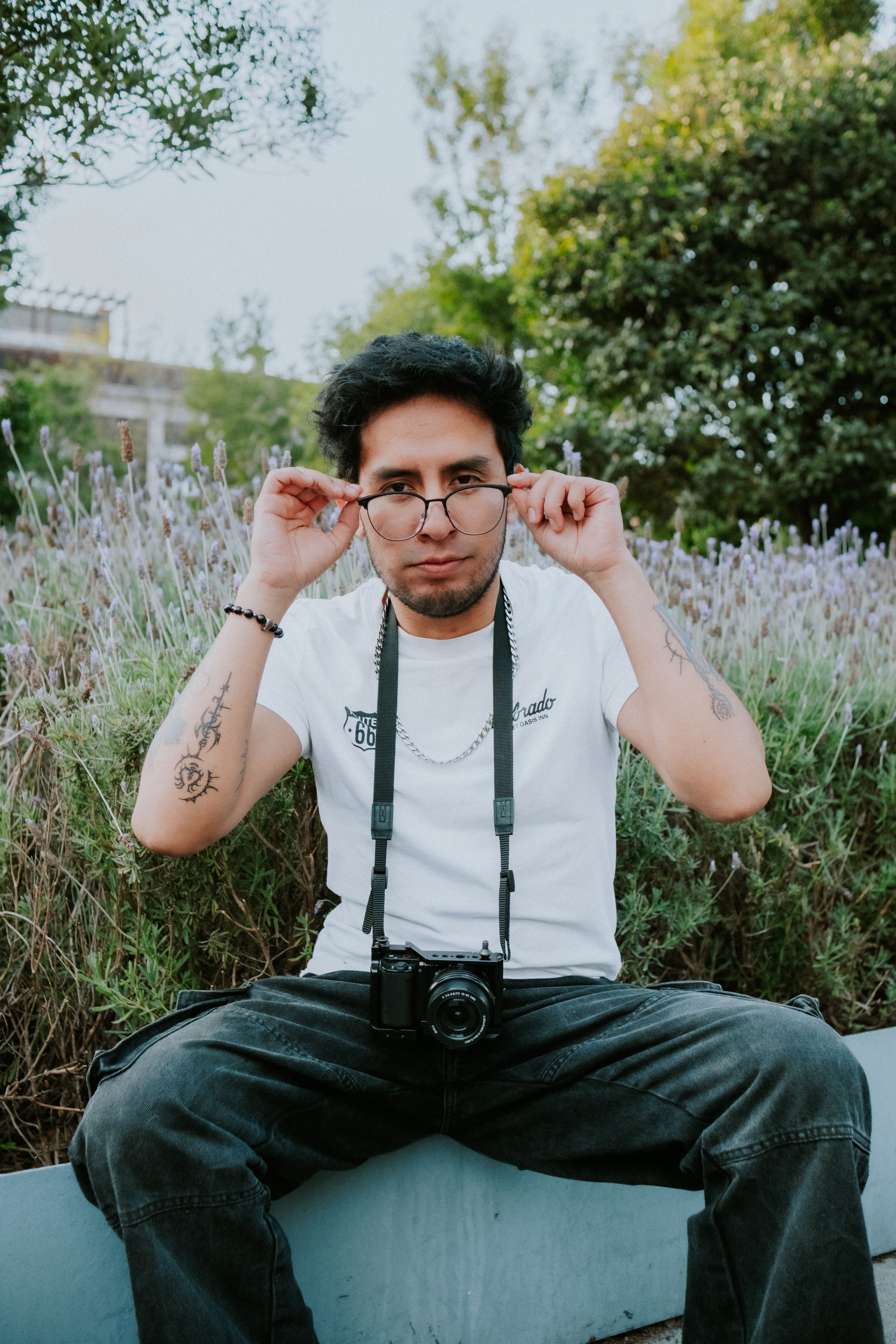 Fotomural Retrato relajado al aire libre de un fotógrafo ajustando sus gafas.