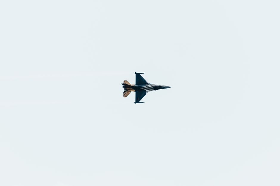 High-altitude jet fighter performing aerial maneuvers against a clear sky backdrop.