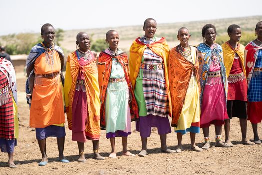 Masai women in colorful traditional attire standing together in Kenya's vibrant landscape.