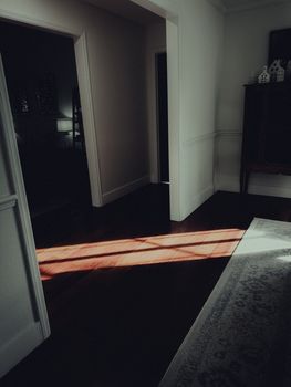 A moody indoor scene capturing sunlight streaming through an open door, creating dramatic shadows.