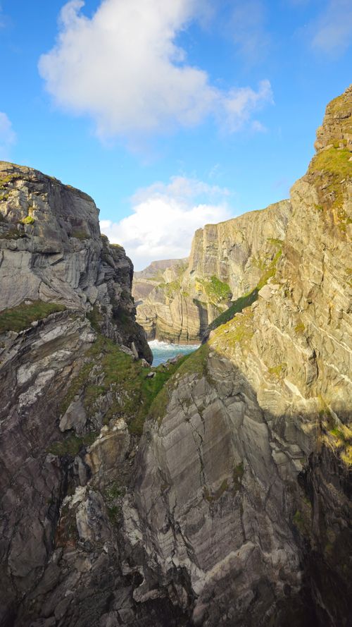 Free Dramatic rocky cliffs with lush vegetation at Mizen Head, Ireland under a bright sky. Stock Photo