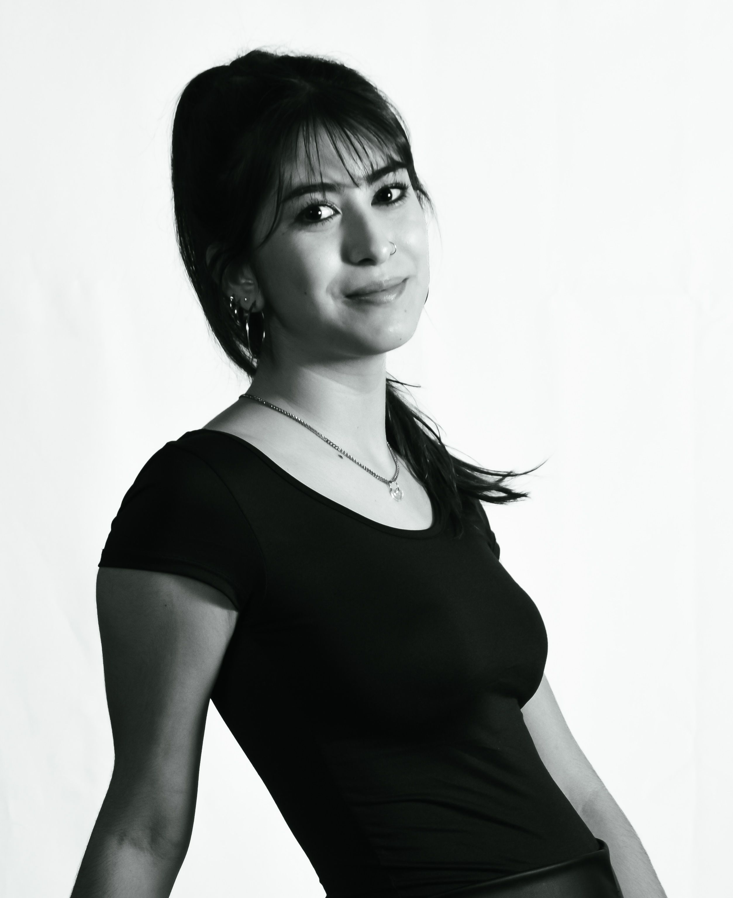 Black and white portrait of a young woman smiling against a plain background.