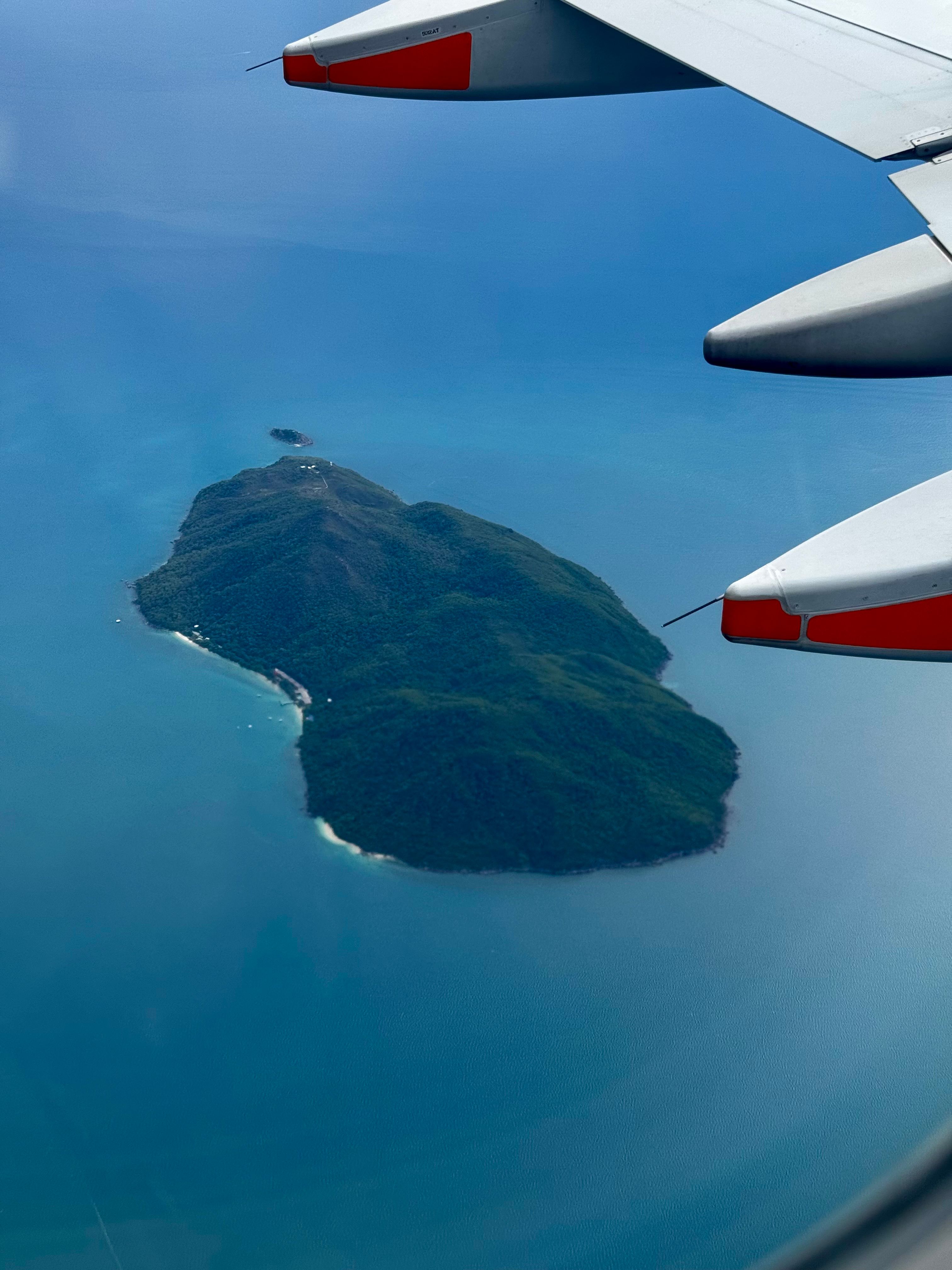 Een adembenemend luchtfoto van een tropisch eiland, gezien vanuit een vliegtuigraam.