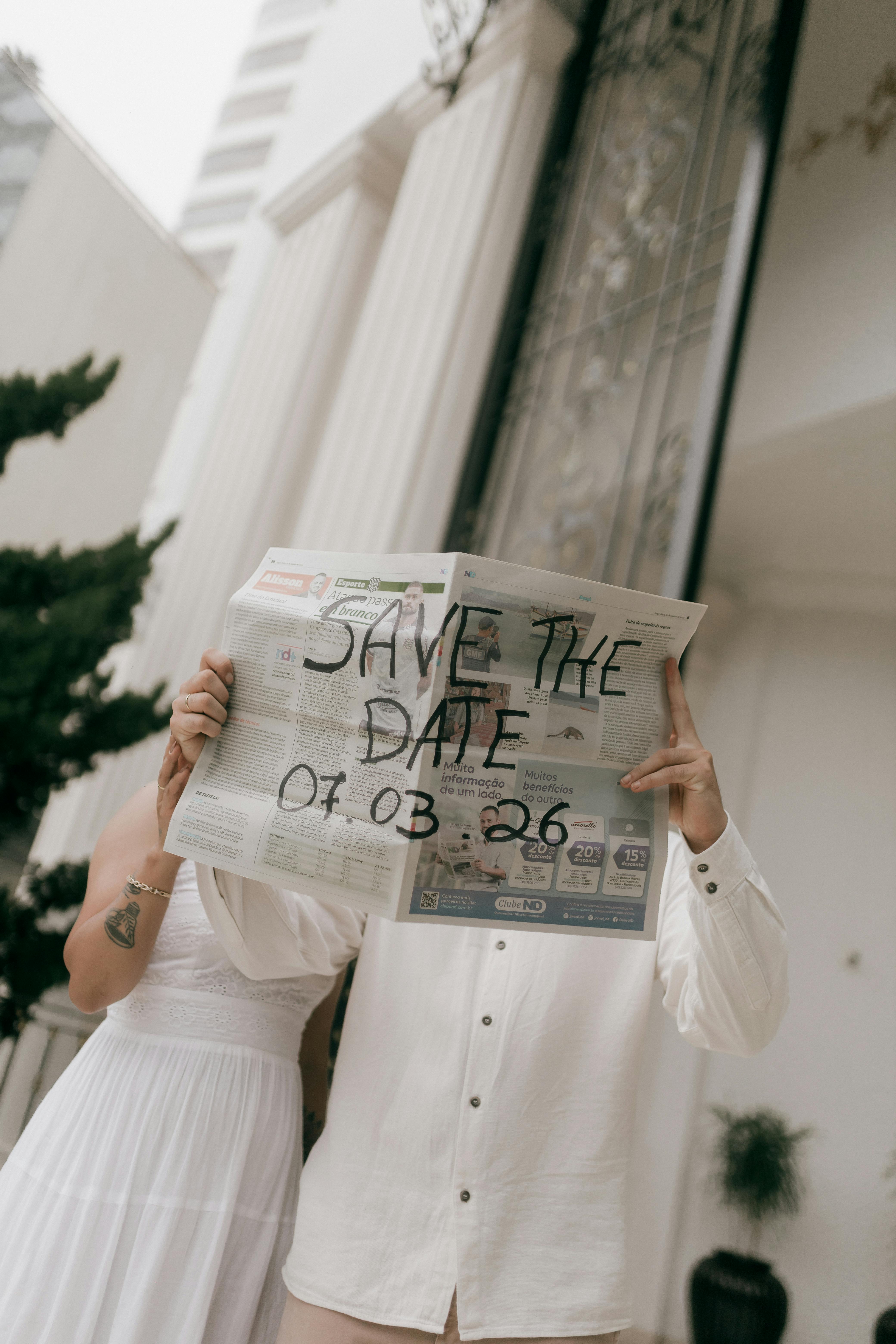 Couple holds newspaper with 'Save the Date' for a wedding announcement.