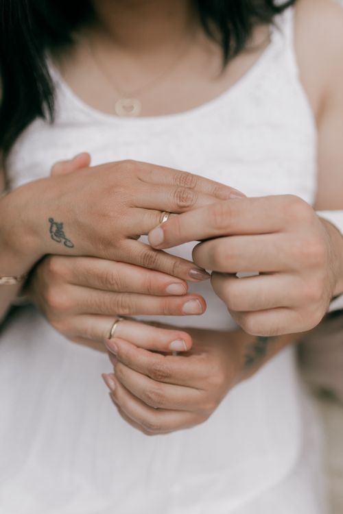 Free Close-up of a couple exchanging wedding rings, showcasing tattoos and a romantic embrace. Stock Photo