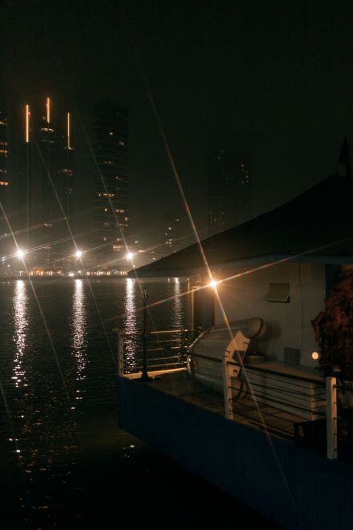 Free Serene night view of an urban skyline with reflections on the water, under soft lighting. Stock Photo
