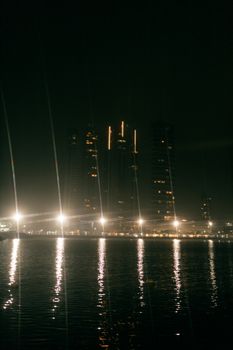 Captivating nighttime cityscape featuring illuminated skyscrapers reflecting on a tranquil waterfront.