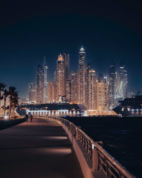 Stunning nighttime view of Dubai Marina skyline with illuminated skyscrapers and docked cruise ships.