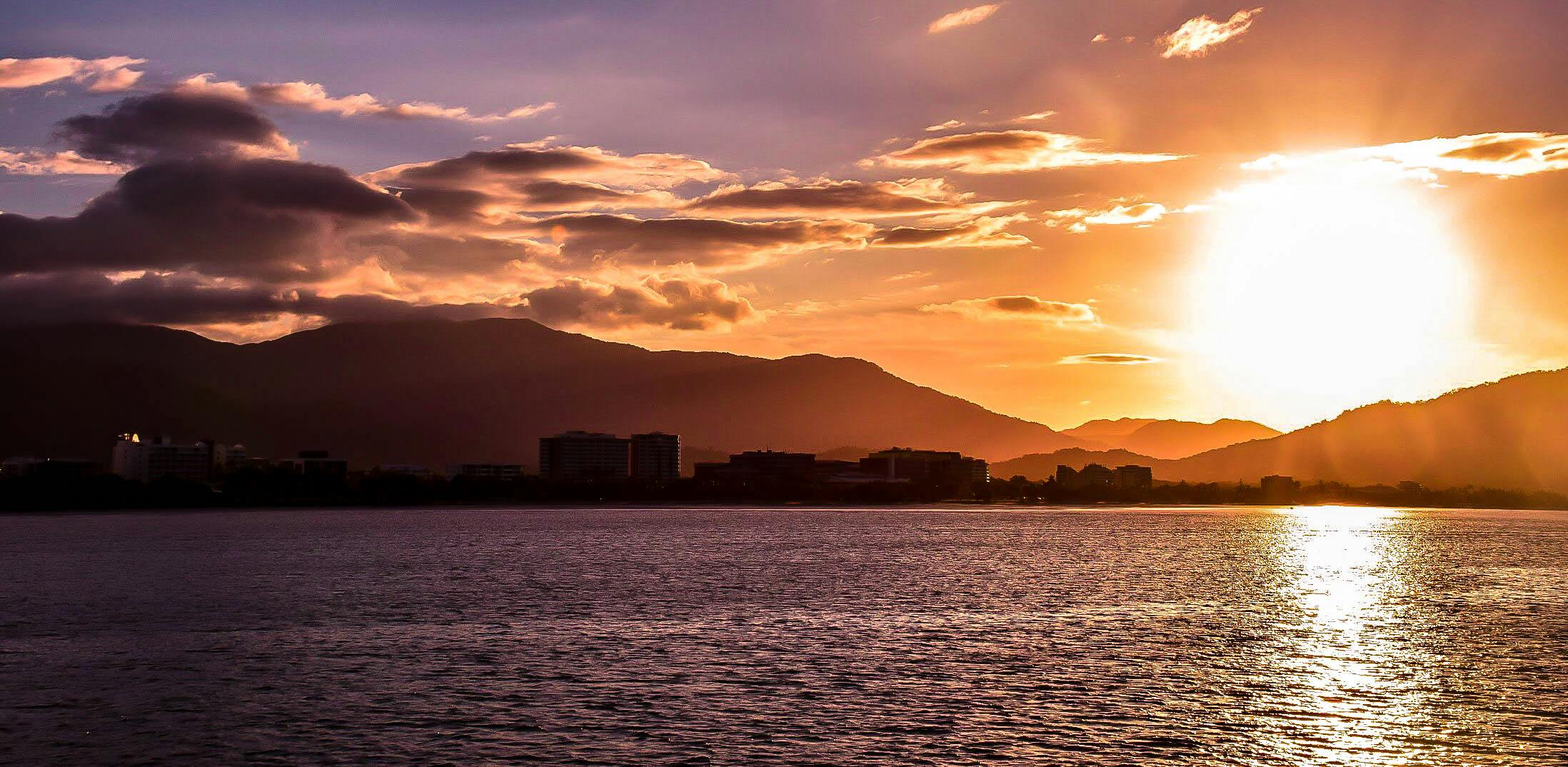在宁静的湖边，充满活力的日落为城市景观和山脉镀上了一层金色
