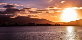 在宁静的湖边，充满活力的日落为城市景观和山脉镀上了一层金色