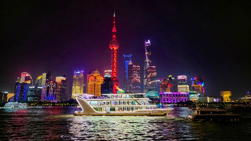 Illuminated Huangpu River night cruise ship passing the Bund