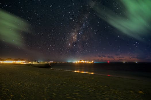 Captivating view of the Milky Way over a serene beach with distant lights, captured under a starry sky.