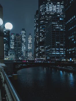 Urban night scene of illuminated skyscrapers reflecting on the water.