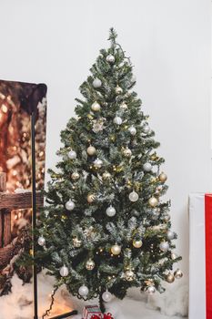 A beautifully adorned Christmas tree with golden and silver ornaments indoors.