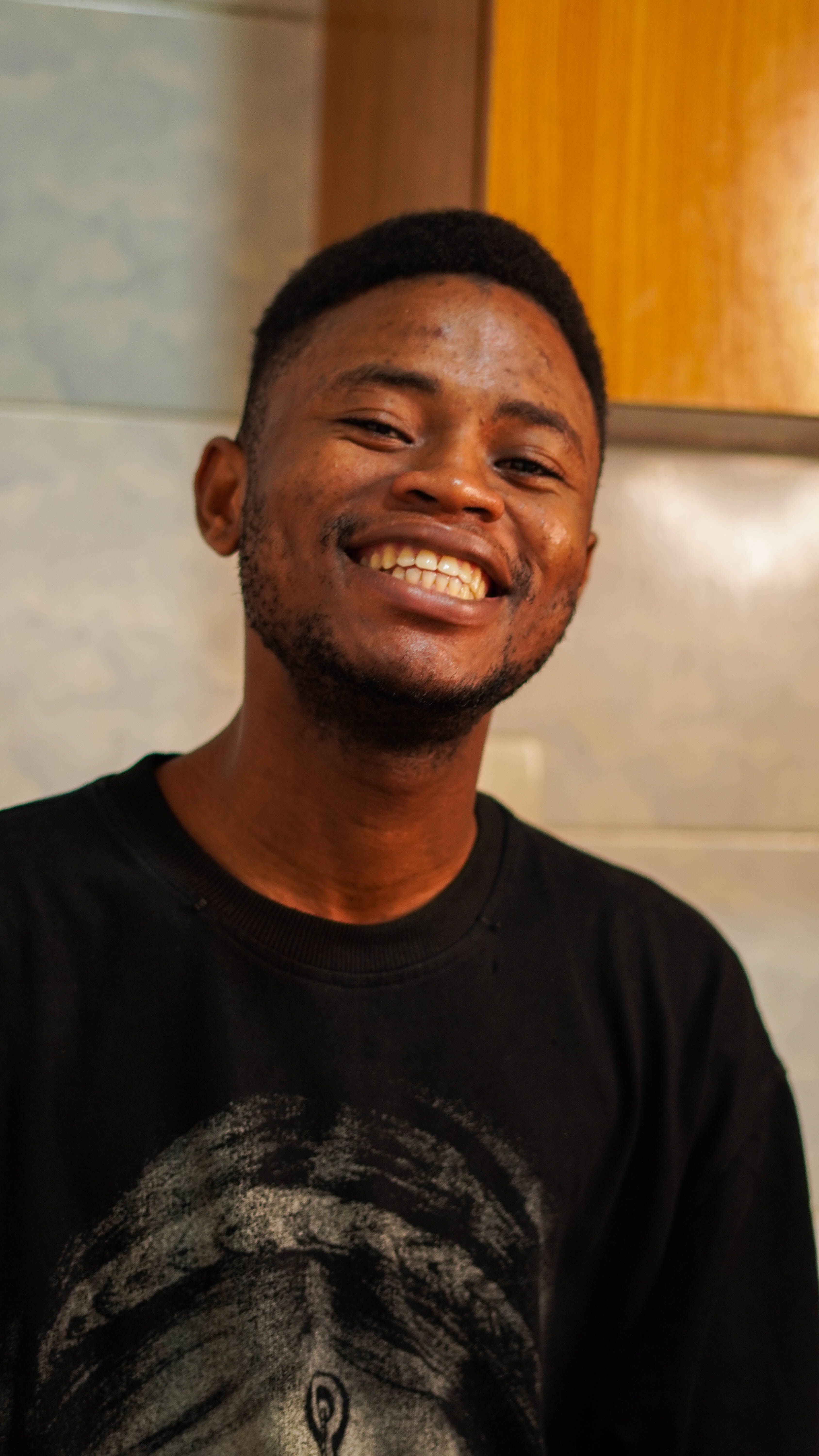 Candid and joyful portrait of a young man with a natural smile and casual attire.