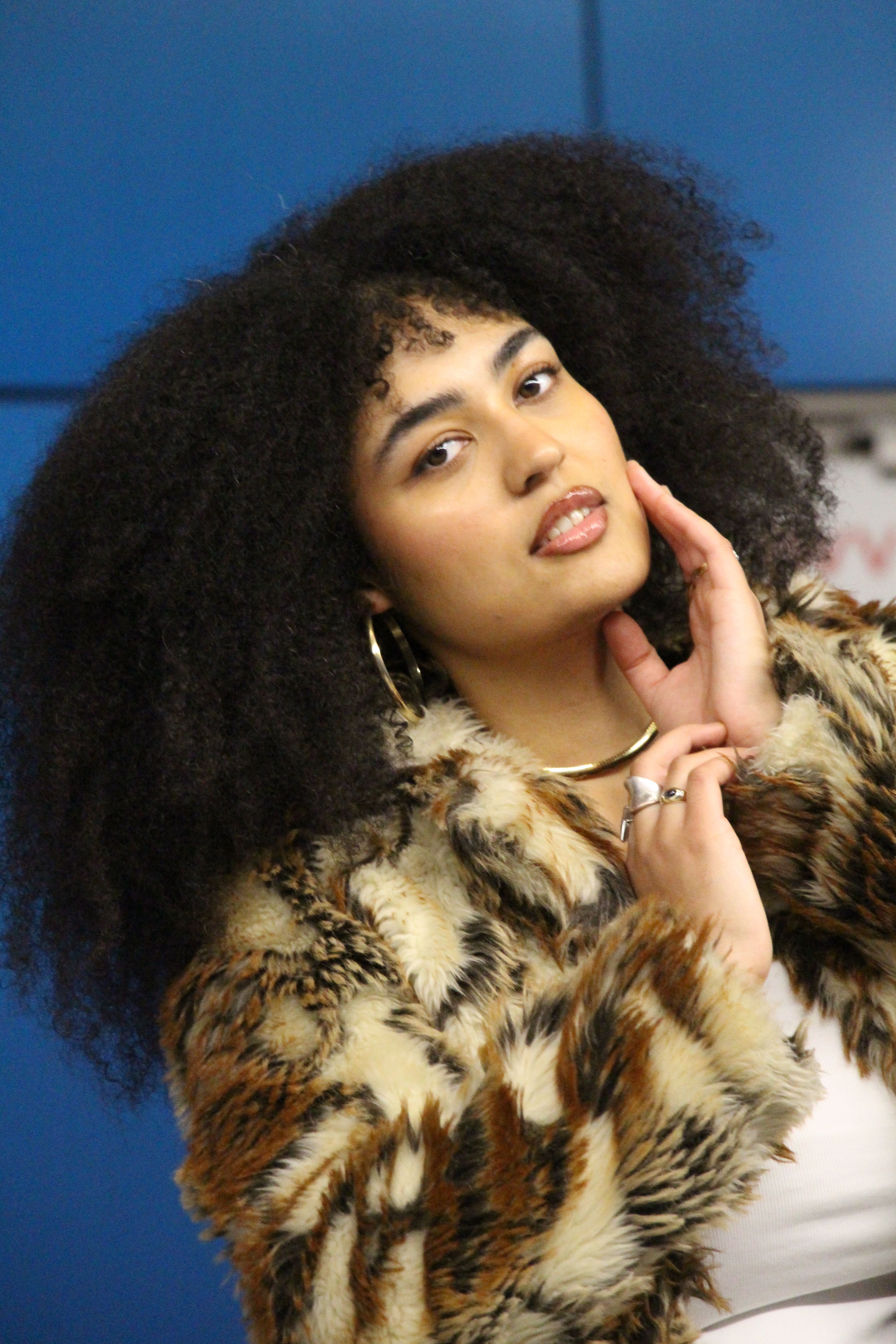 Portrait of a fashionable woman posing indoors wearing a fur coat.
