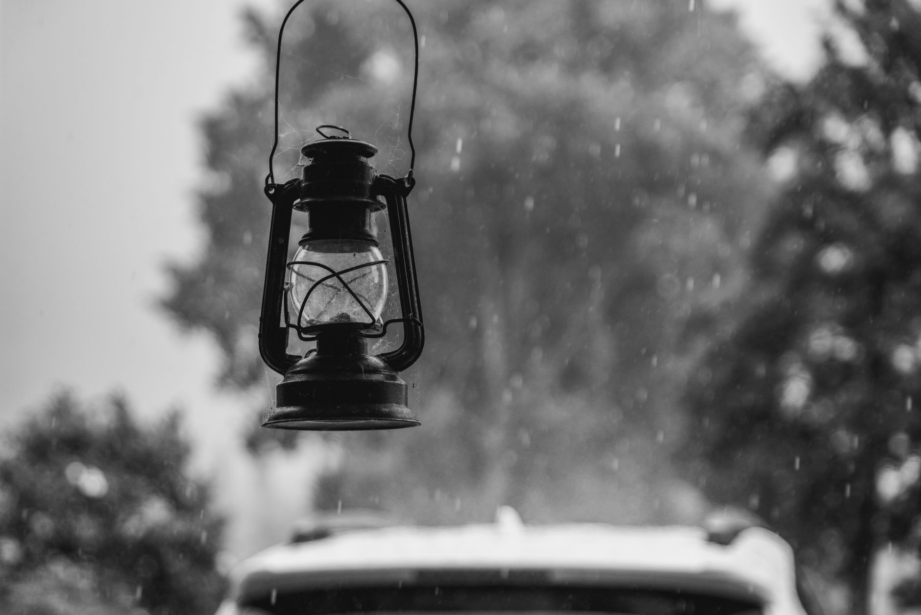 手機露營升級:燈光分層與電力智慧控制 A vintage oil lantern in a rainy outdoor setting, illustrating warm mood lighting under shelter.