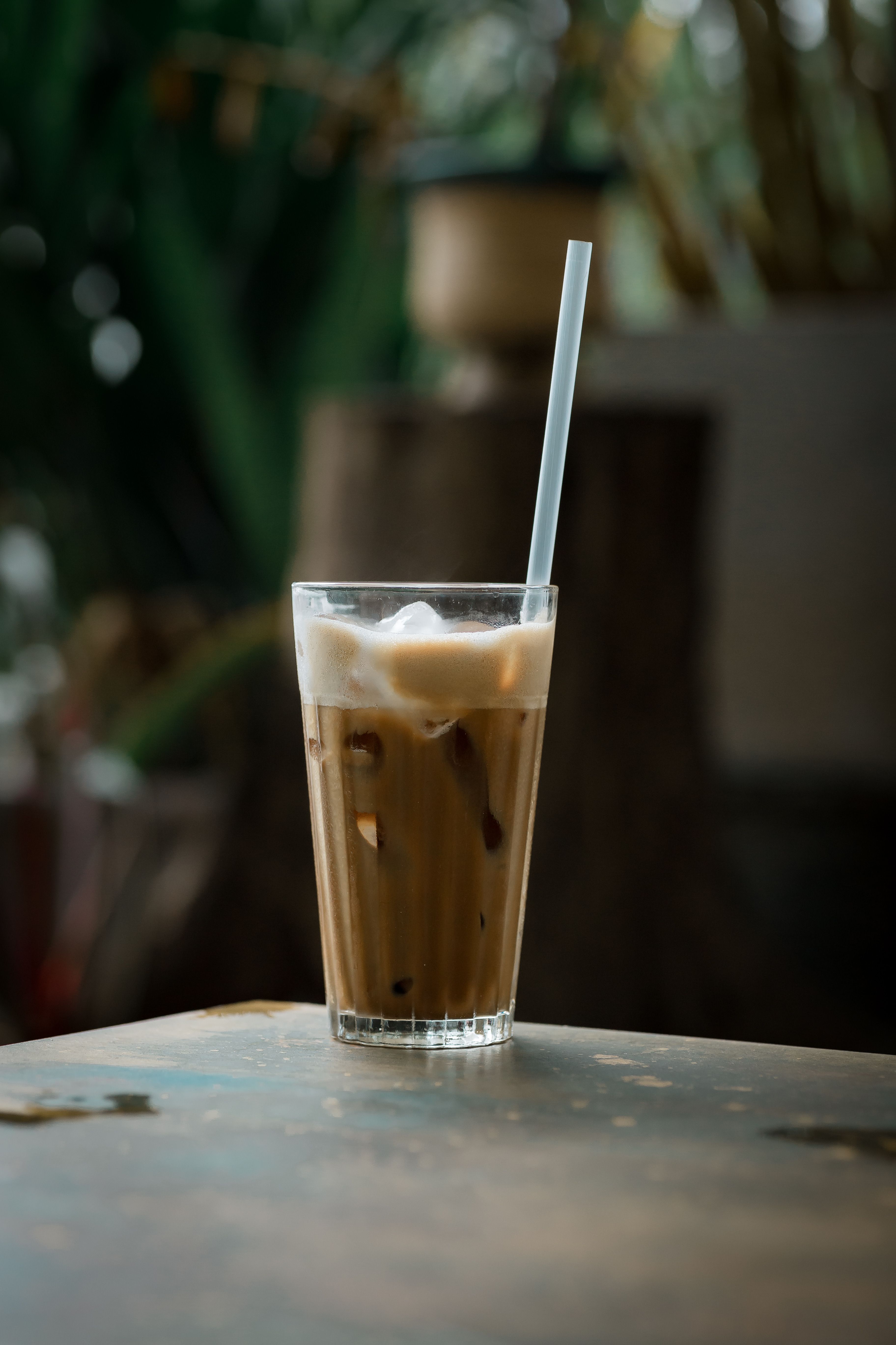Close-up of a refreshing iced coffee in a glass with a straw on a rustic table.