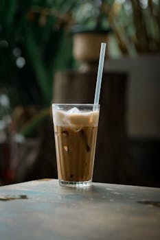 Close-up of a refreshing iced coffee in a glass with a straw on a rustic table.