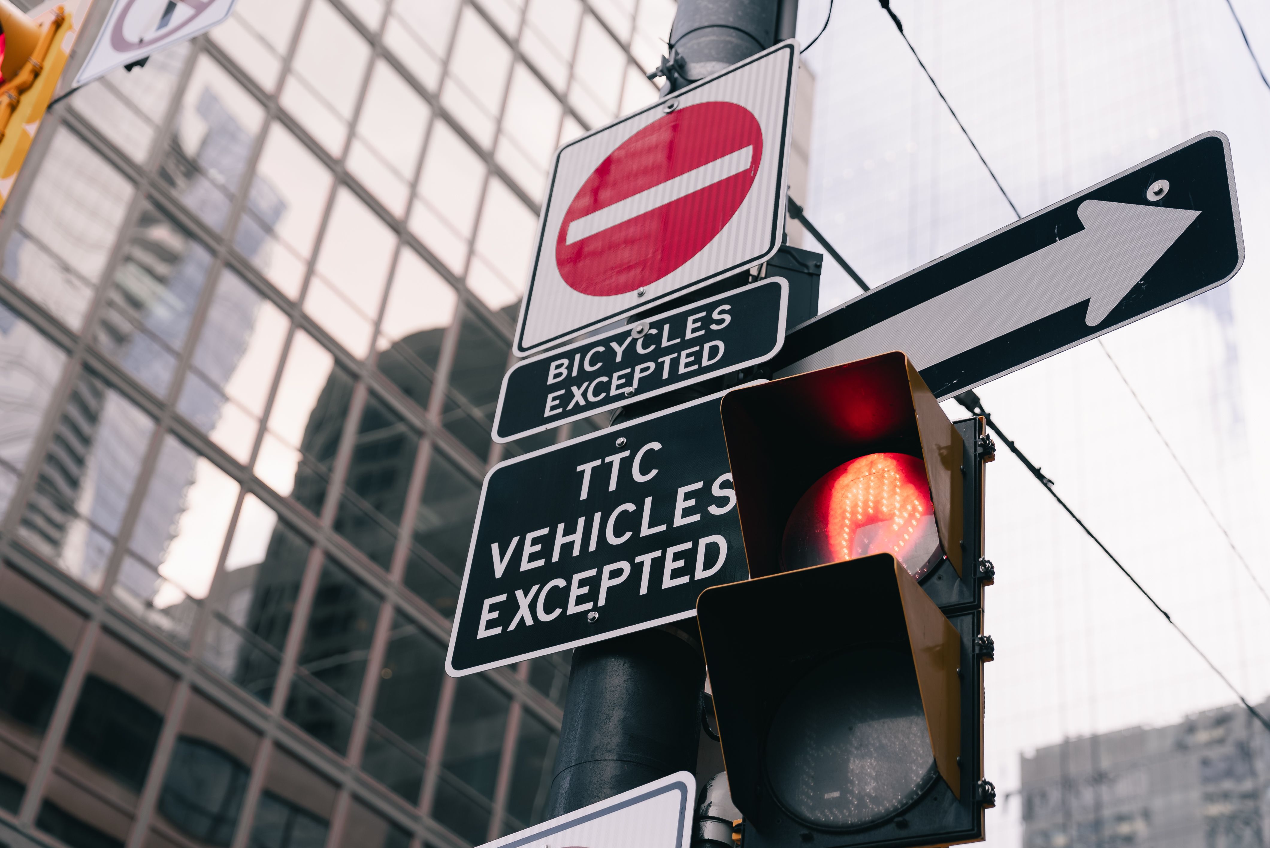 Urban traffic light and signs with building reflection in downtown Toronto.