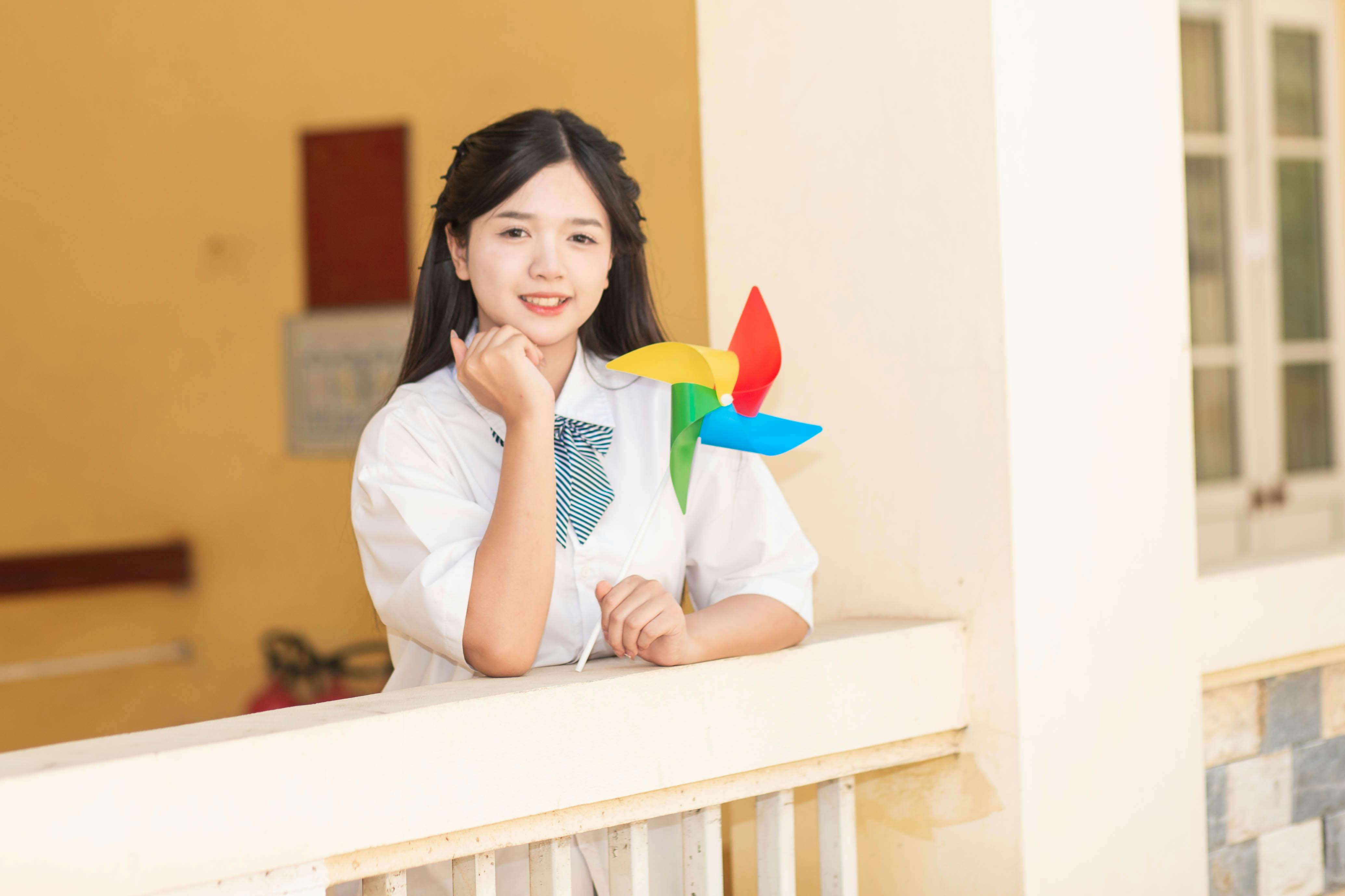 免費 年輕女子手持色彩鮮豔的風車，神態愉悅。 圖庫相片