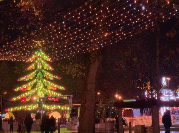 Sapin de Noël illuminé et guirlandes lumineuses sur un marché de Noël nocturne