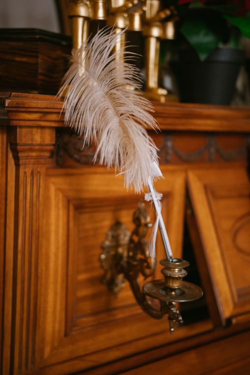 Free An elegant feather quill pen rests on a vintage wooden desk, evoking a sense of history and sophistication. Stock Photo