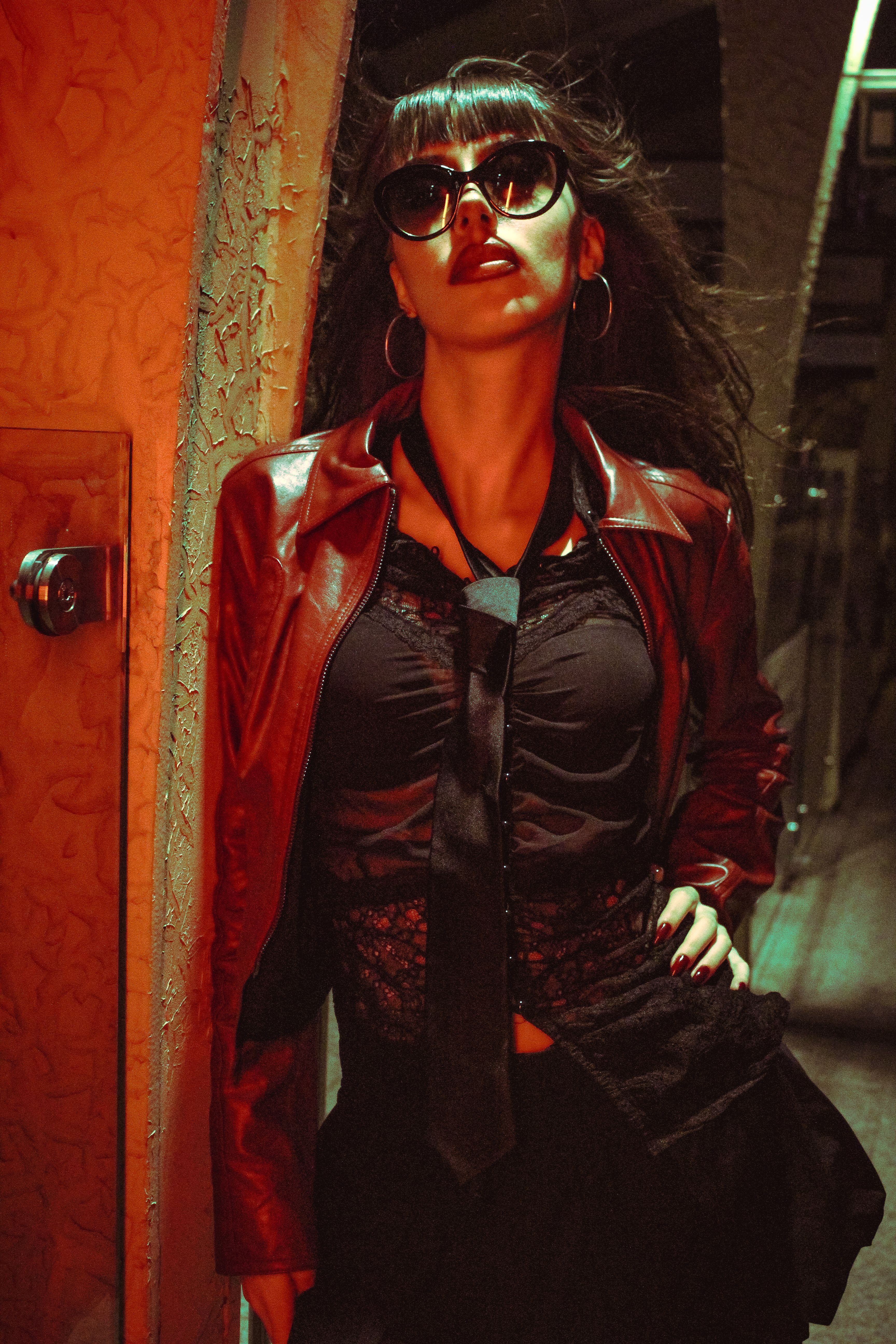 Woman in leather jacket over red slip dress